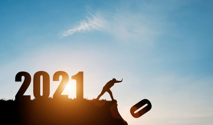 Man push number zero down the cliff where has the number 2021 with blue sky and sunrise. It is symbol of starting and welcome happy new year 2021.