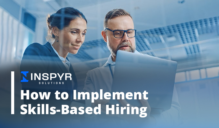 Two professionals look at a laptop screen, showcasing a guide titled How to Implement Skills-Based Hiring by Inspyr Solutions. The office backdrop features modern lighting, perfectly setting the scene for innovative hiring strategies.