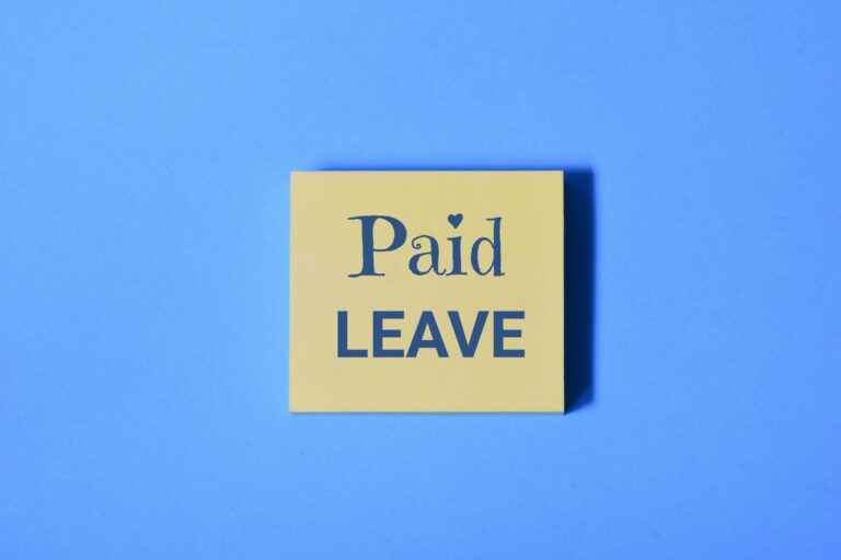 A yellow sticky note with the words Paid Leave in bold letters stands out against a blue background, symbolizing the expanding reach of Paid State Leave Laws.