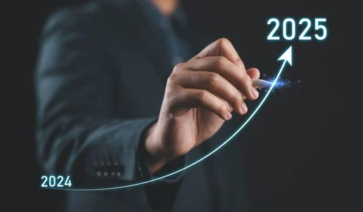 A person in a suit draws an upward curved arrow from 2024 to 2025, symbolizing growth or progress, on a dark background—perfect imagery for an Industry Report 2025 or State of the Industry update.